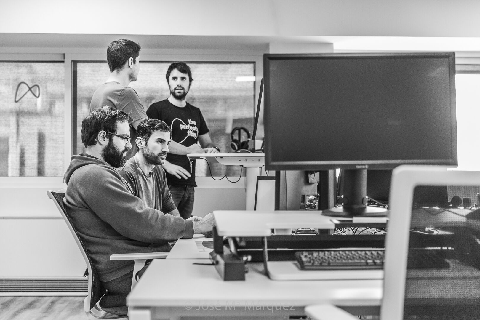 Reportaje corporativo para la empresa Novatec, compañeros trabajando en un proyecto en equipo Cuatro chicos comentando un proyecto en una fotografía de reportaje corporativo de empresa en Granada