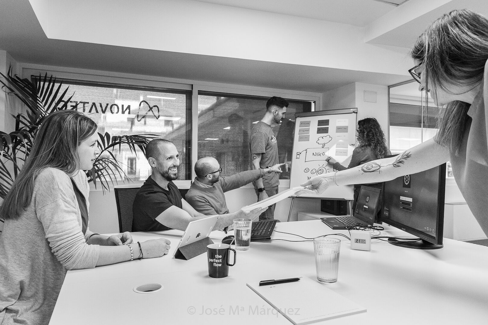 Fotografía de reportaje corporativo, chica entrega informe durante una reunión de la empresa Novatec en Granada Una chica entrega un informe durante una reunión, fotografía realizada por José María Márquez, fotógrafo de Granada para la empresa Novatec