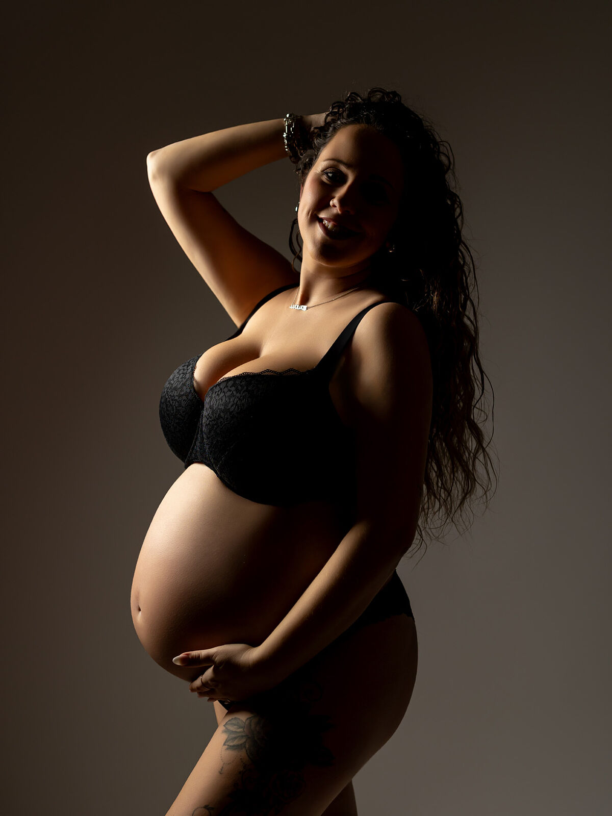 Retrato de mujer embarazada con ropa interior negra y pose segura bajo luz controlada, durante sesión profesional en estudio en Cartagena por Torres & Torres Fotografía