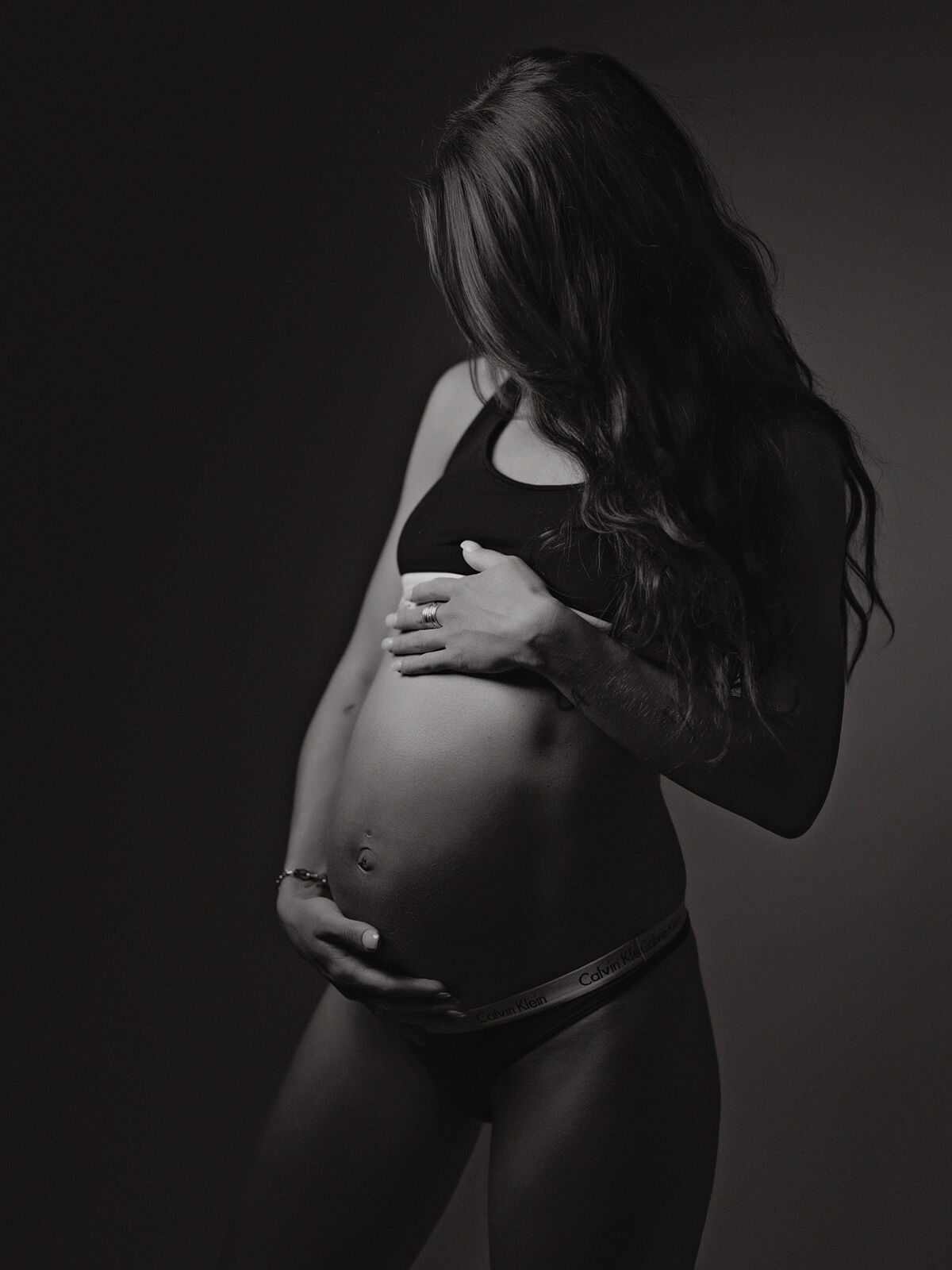 Retrato en blanco y negro de mujer embarazada sujetando su vientre, realizado en estudio profesional en Cartagena por Torres & Torres Fotografía
