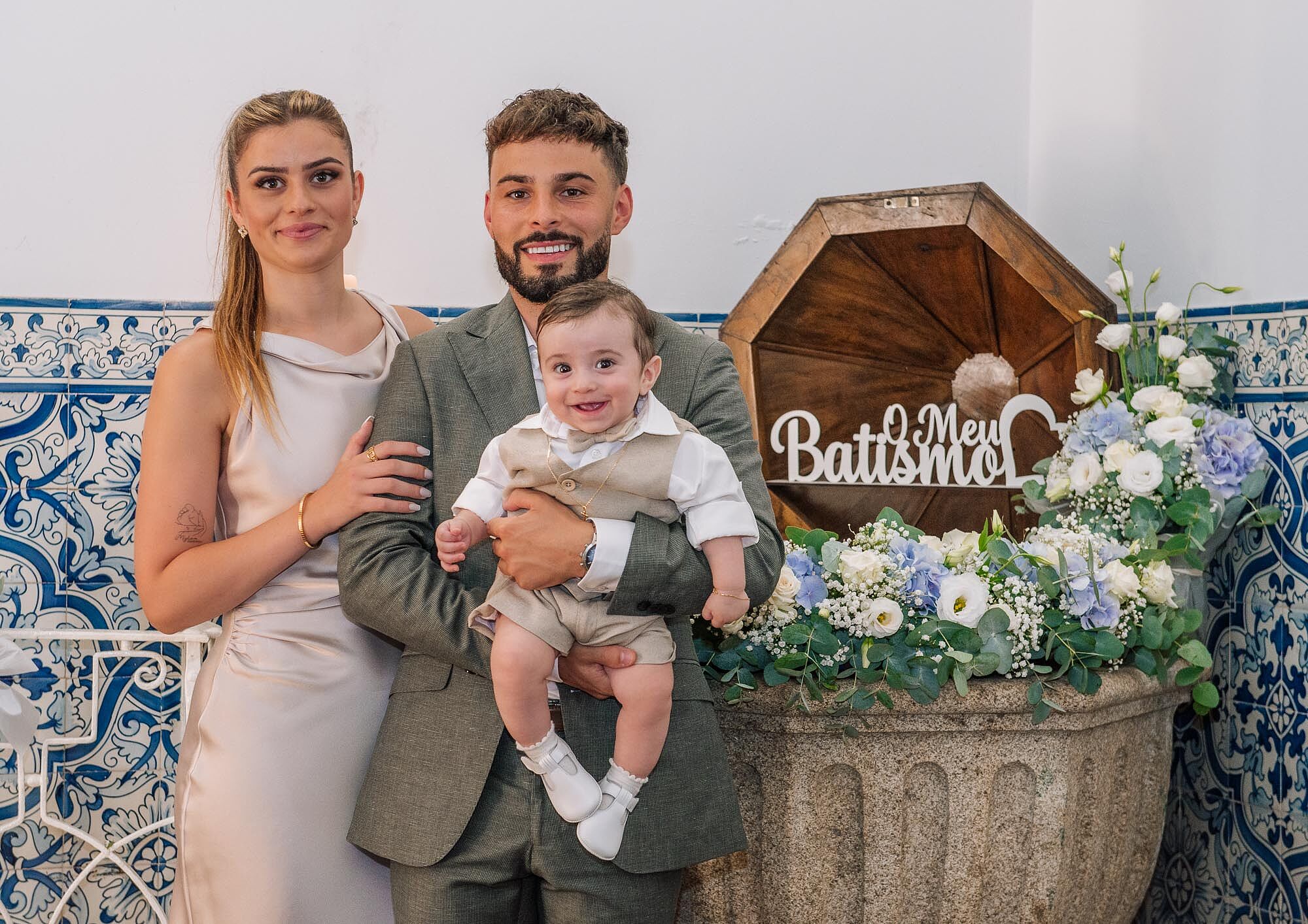 pais e bebe junto á pia do batismo