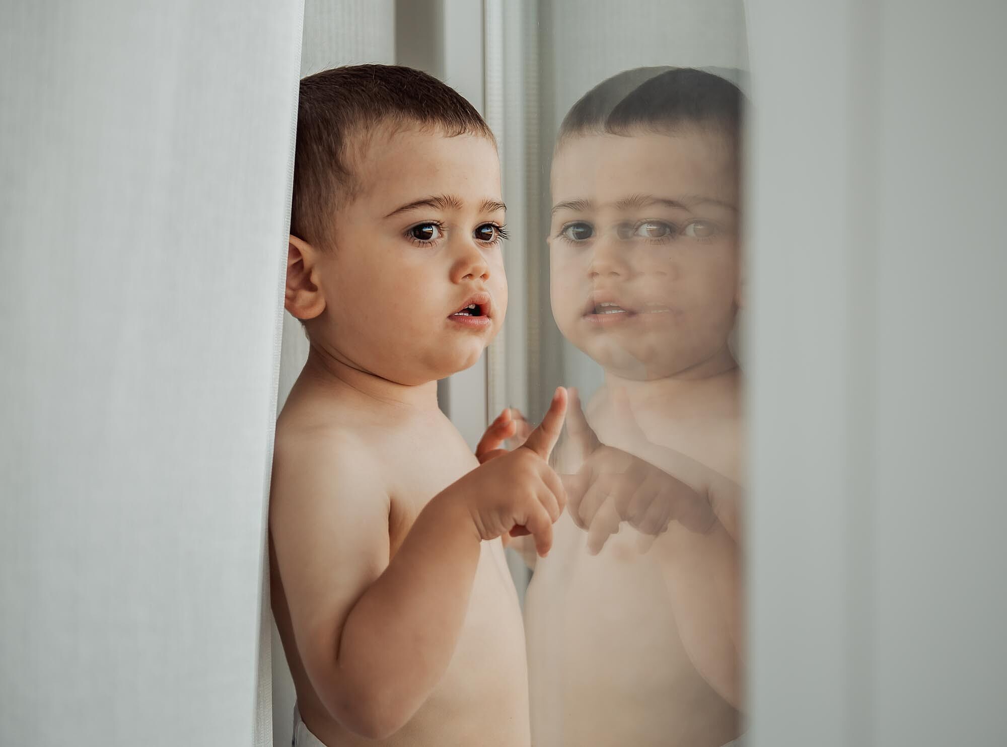 criança junto á janela onde podemos ver o seu reflexo