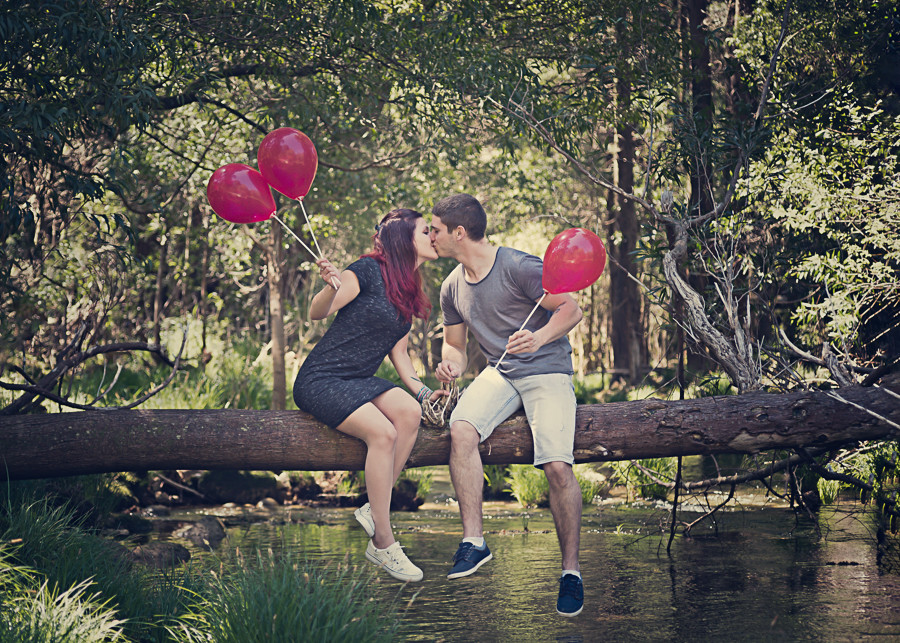 Casal de namorados e segurar balões e sentados num ramo de uma árvore