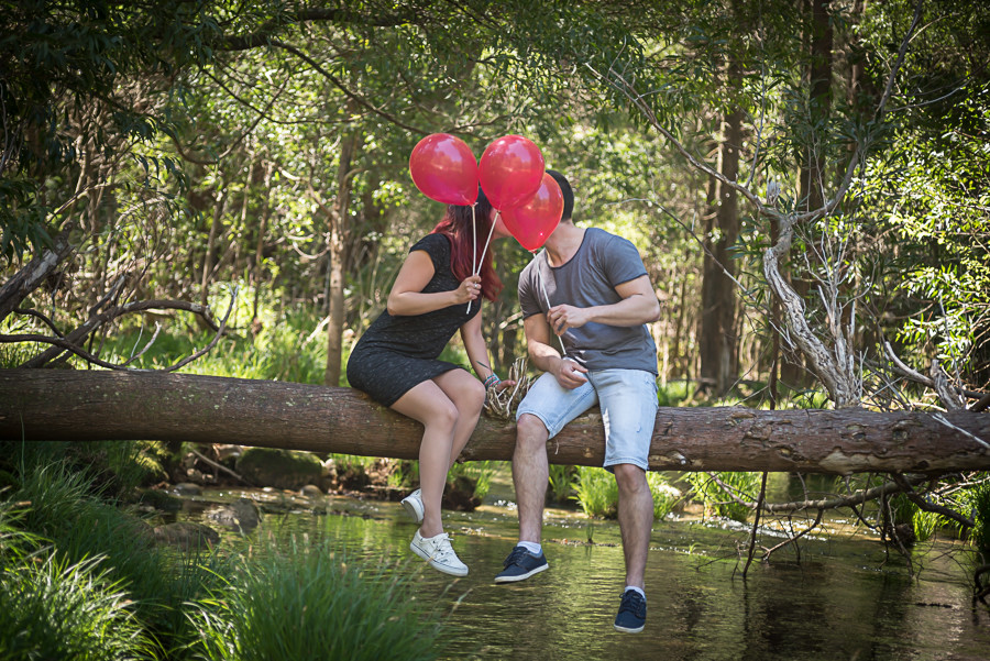 Casal de namorados a dar um beijo e a tapá-lo com os balões