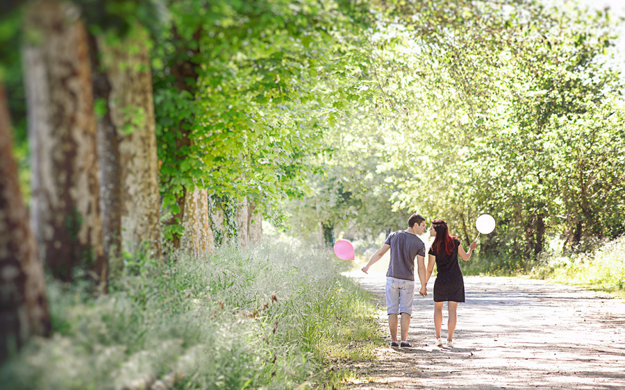 Casal de namorados a caminharem de mãos dadas a olharem um para o outro