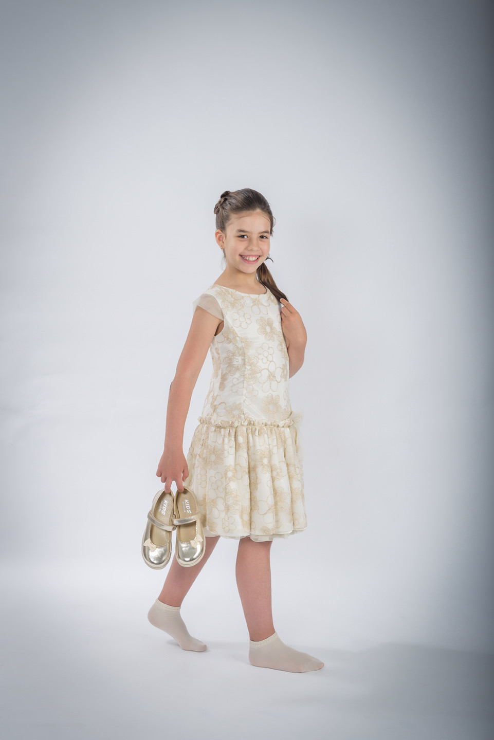 Menina de vestido a segurar os sapatos enquanto caminha