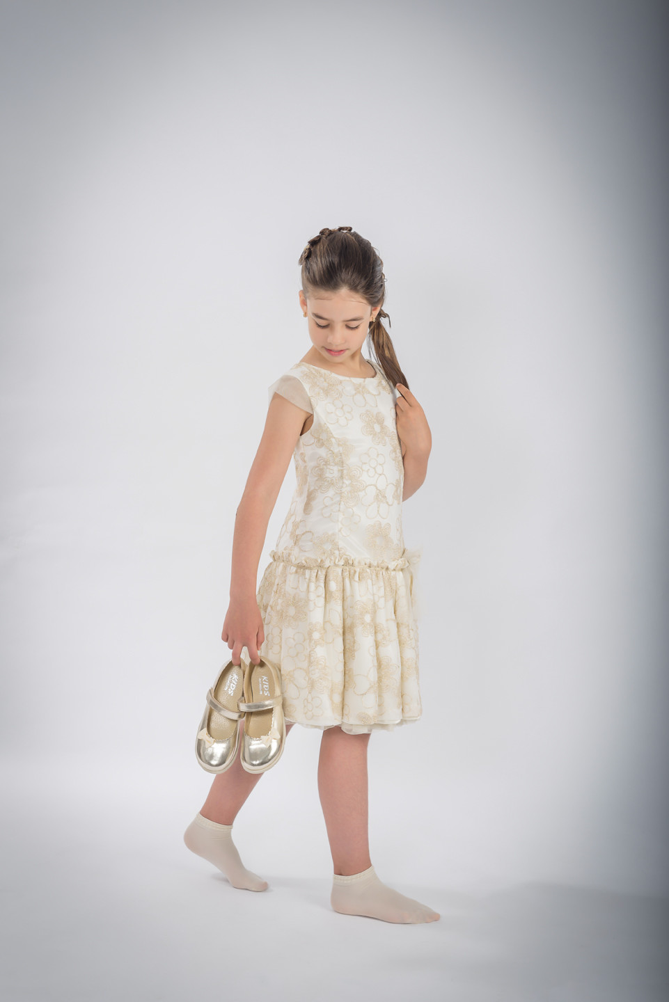 Menina de vestido a segurar os sapatos enquanto olha para eles