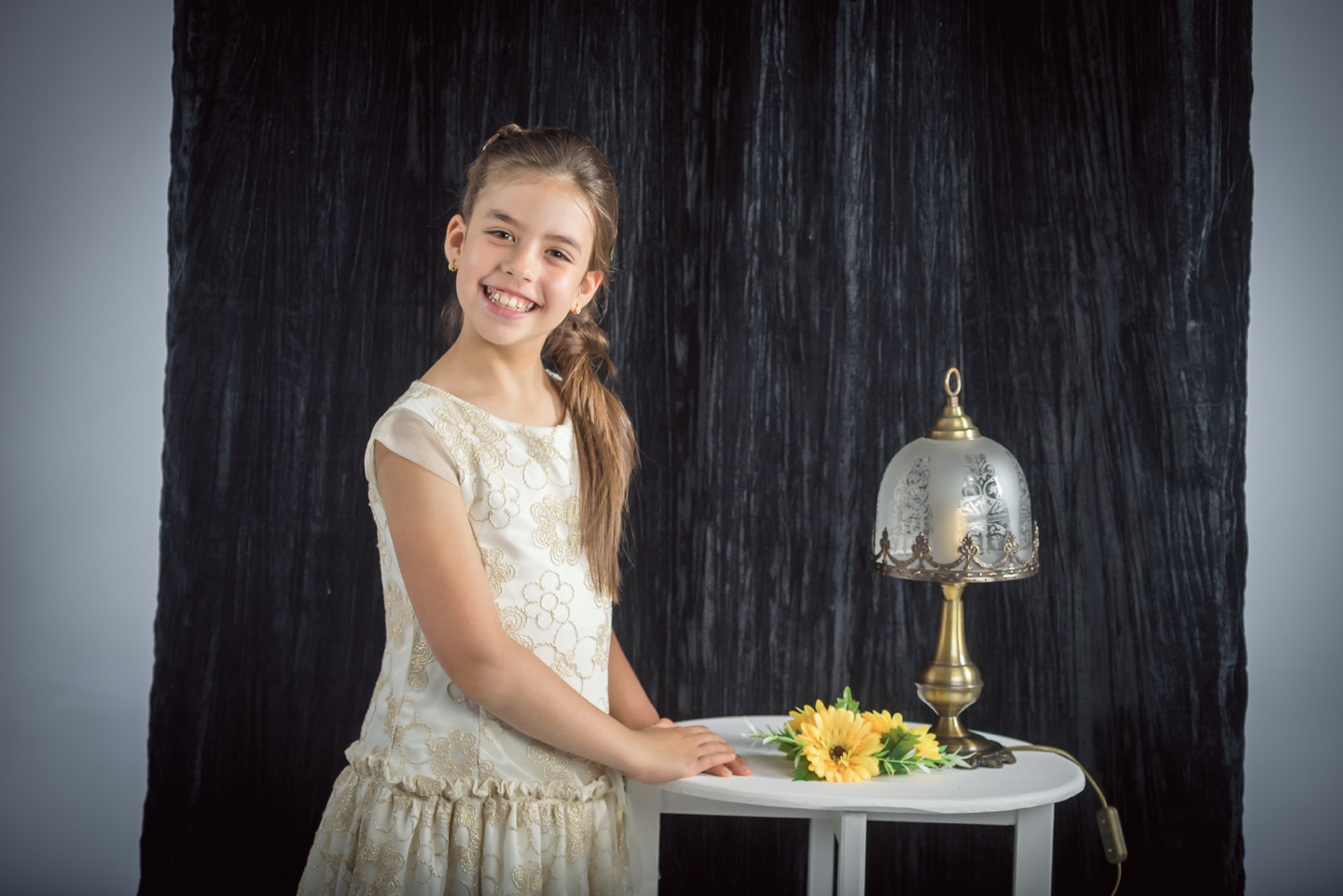 Menina de vestido a sorrir a beira de um candeeiro e de flores