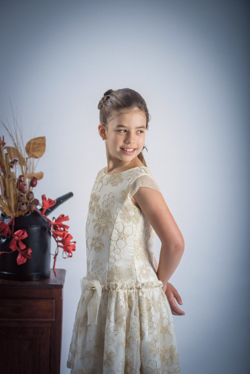 Menina de vestido com as mãos nas costas a olhar para o lado