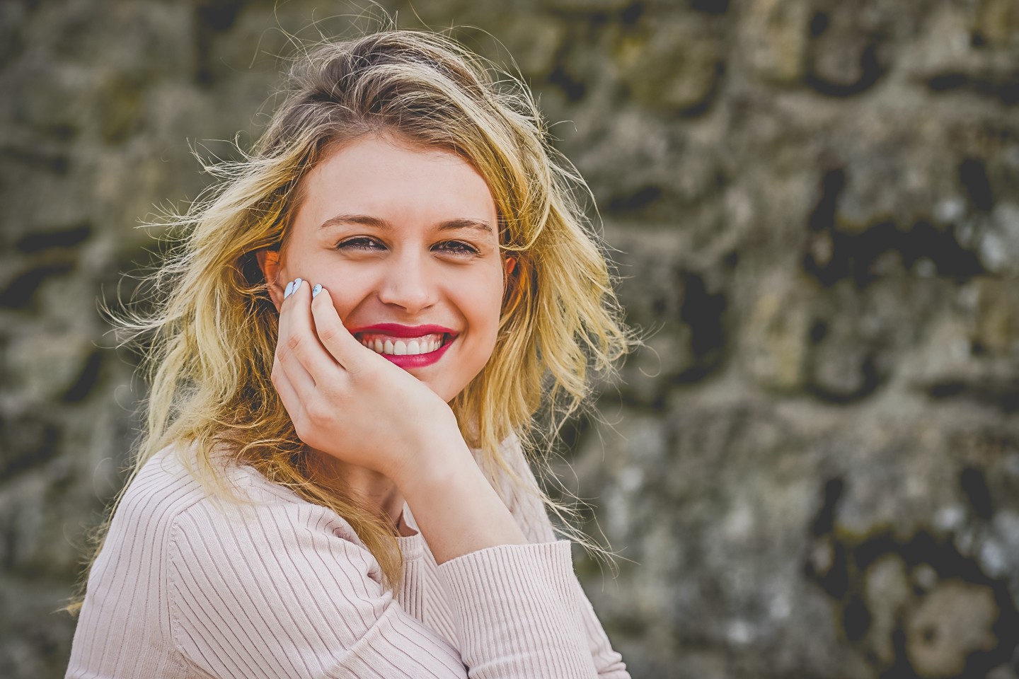 Mulher com a m&atilde;o a segurara a cabe&ccedil;a e a sorrir