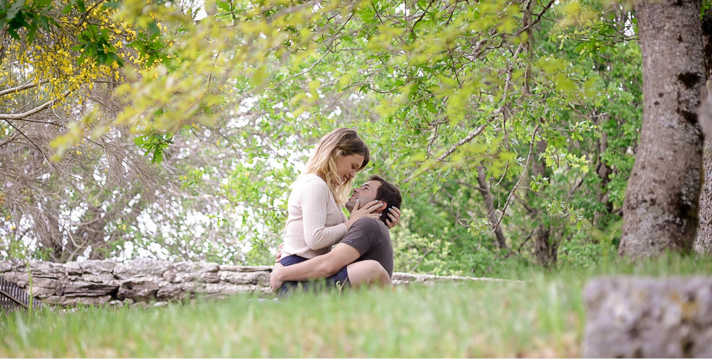 Casal de namorados a olharem apaixonadamente um para o outro enquanto est&atilde;o sentados na relva