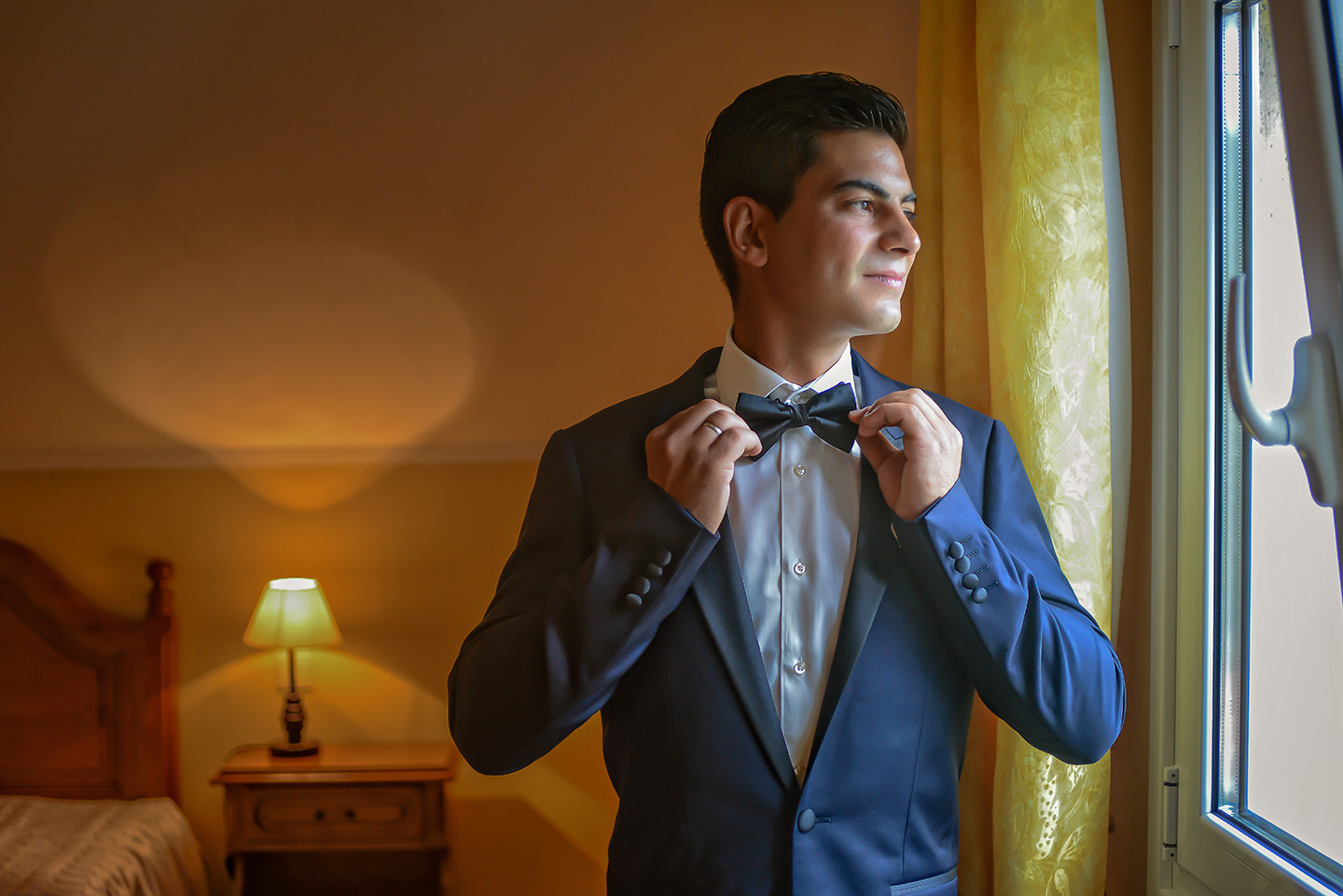 Noivo de fato azul a arranjar o laço