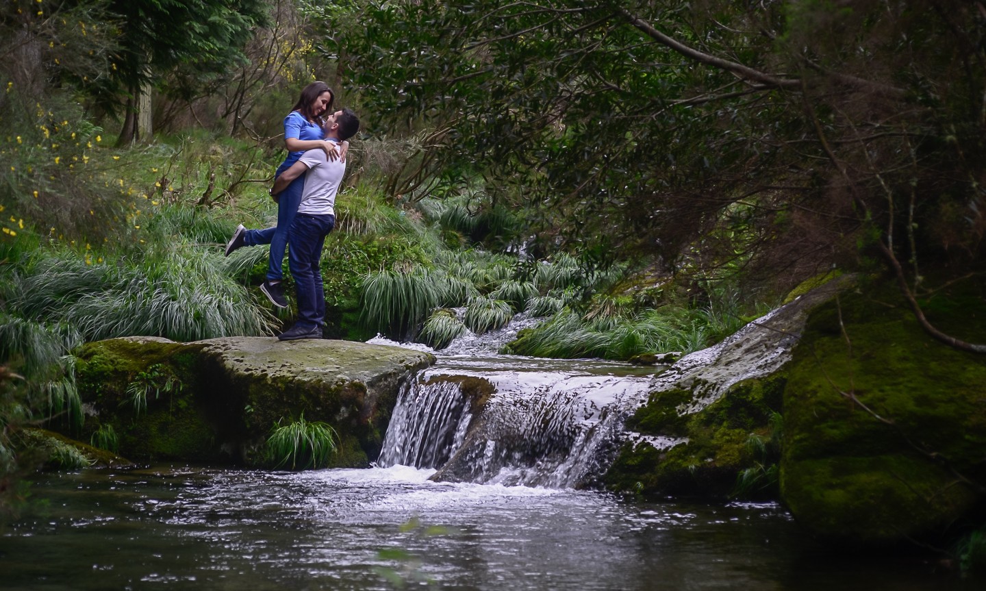 Homem a pegar ao colo a namorada a beira de um lago