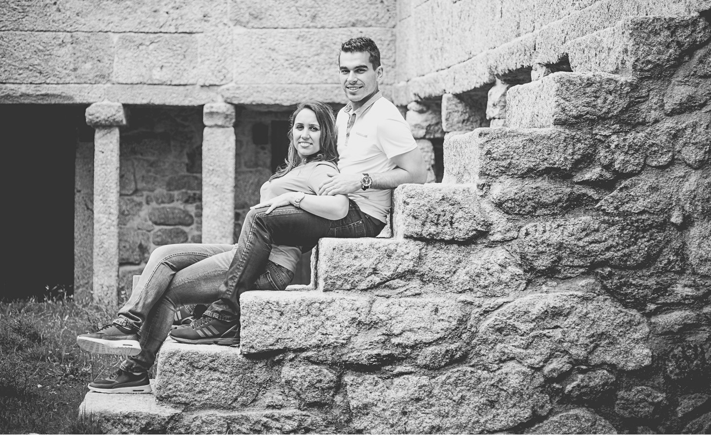 Casal de namorados sentados nas escadas onde o homem está com a mão no braço da mulher