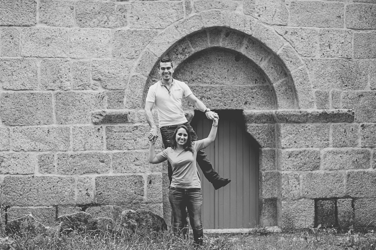 Homem em cima de uma pedra enquanto dá as mãos a namorada