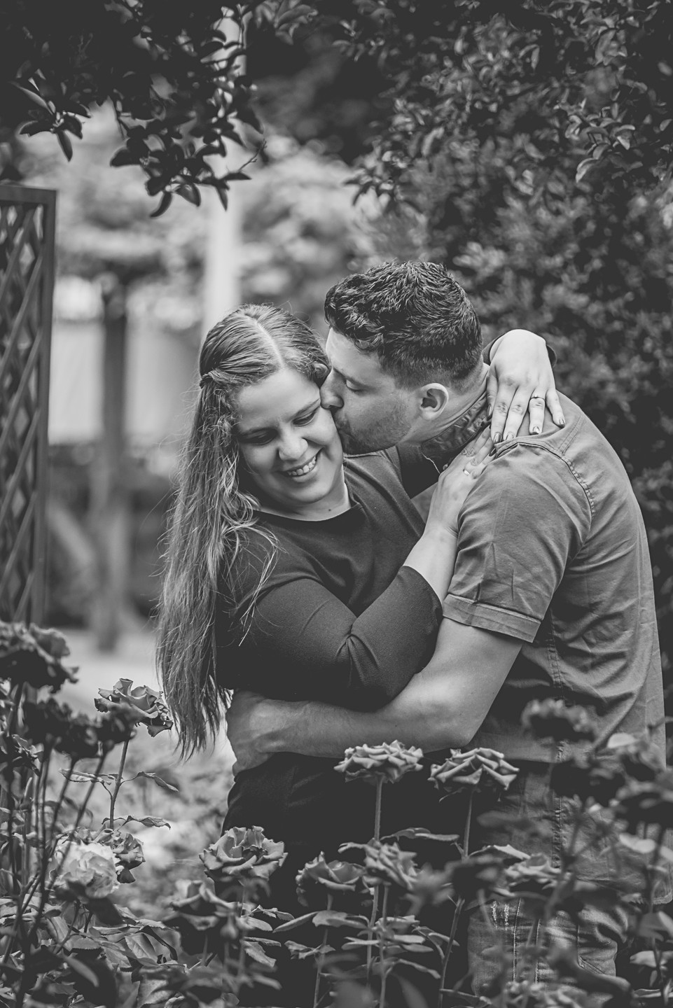 Casal a dar um abra&ccedil;o enquanto o homem d&aacute; um beijo na bochecha