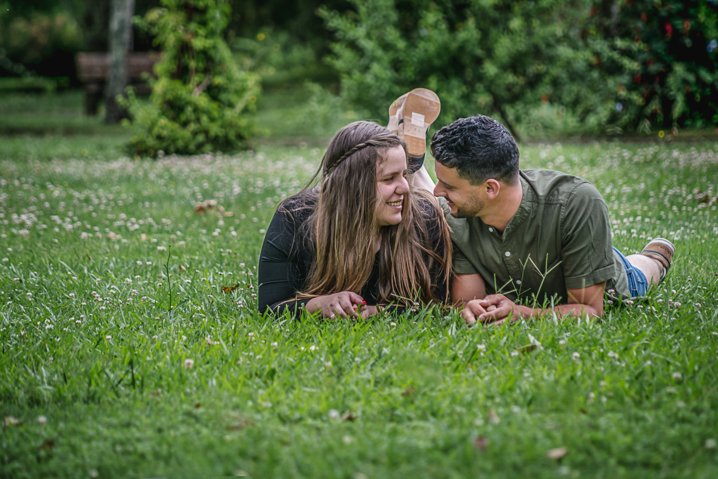 Casal de namorados deitados na relva e a sorrirem um para o outro