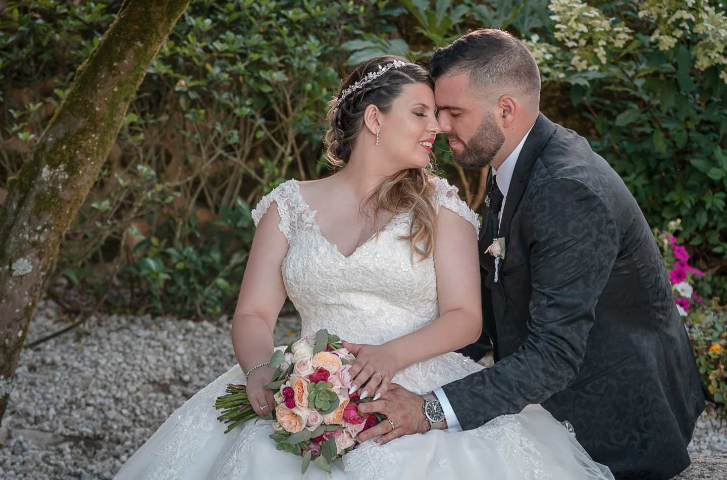 Noivos com a cabeça encostada uma na outra e sentados num banco