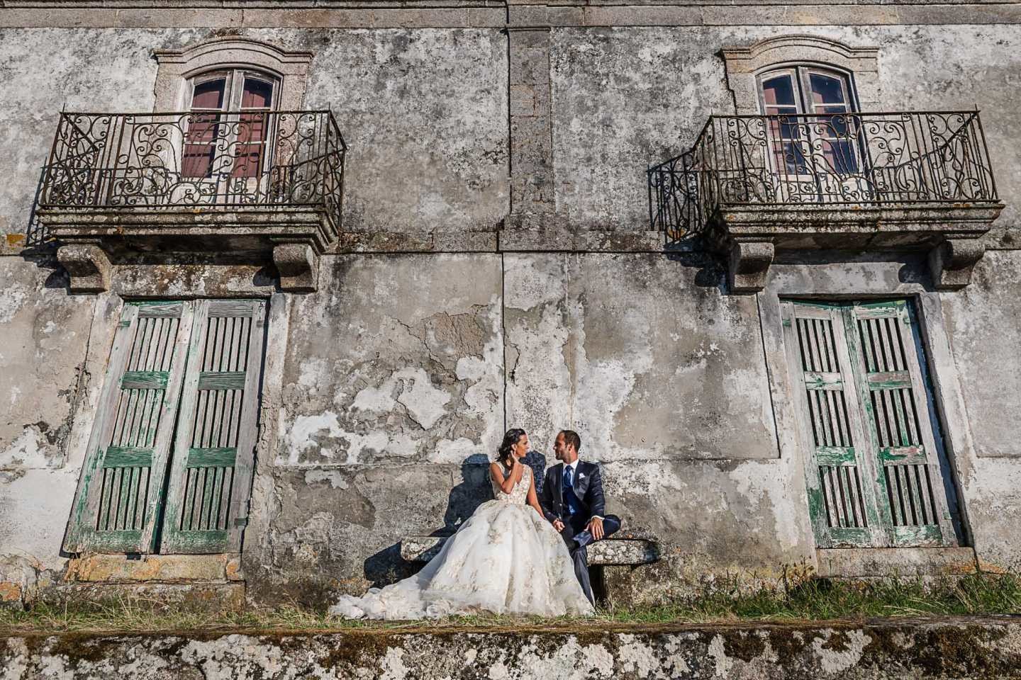 Noivos sentados num banco a olharem um para o outro