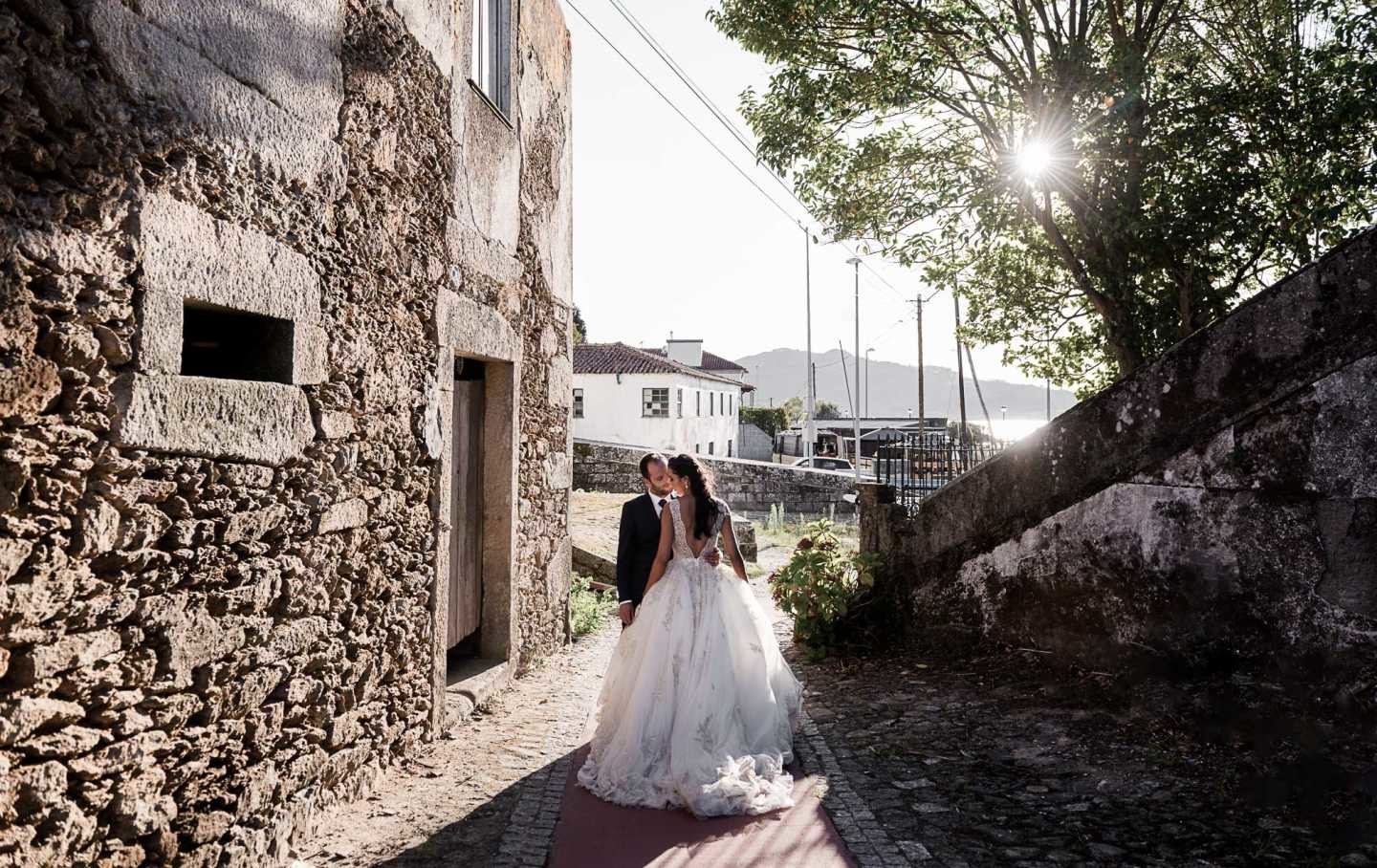 Noivos a beira de uma casa de costas para a camara