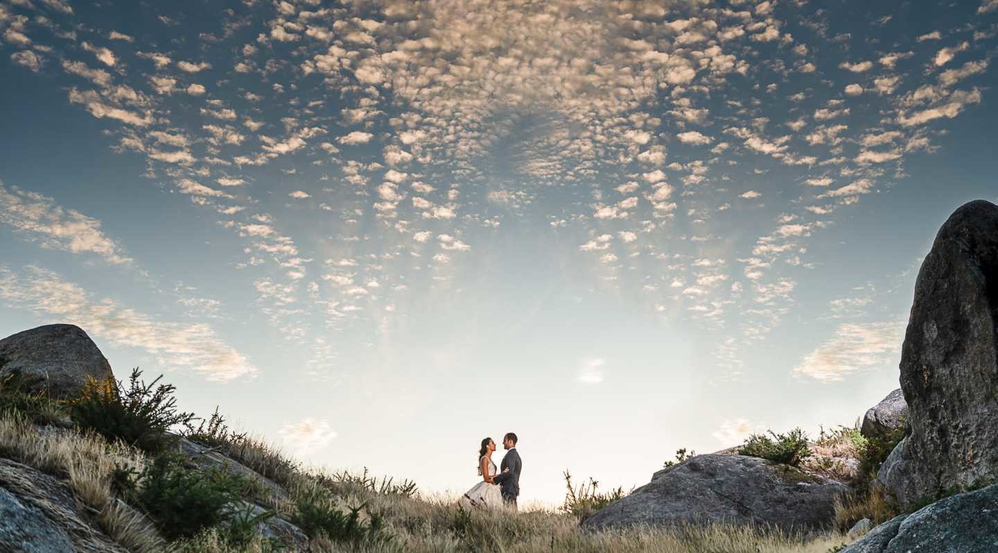 Noivos a darem as mãos no meio das rochas