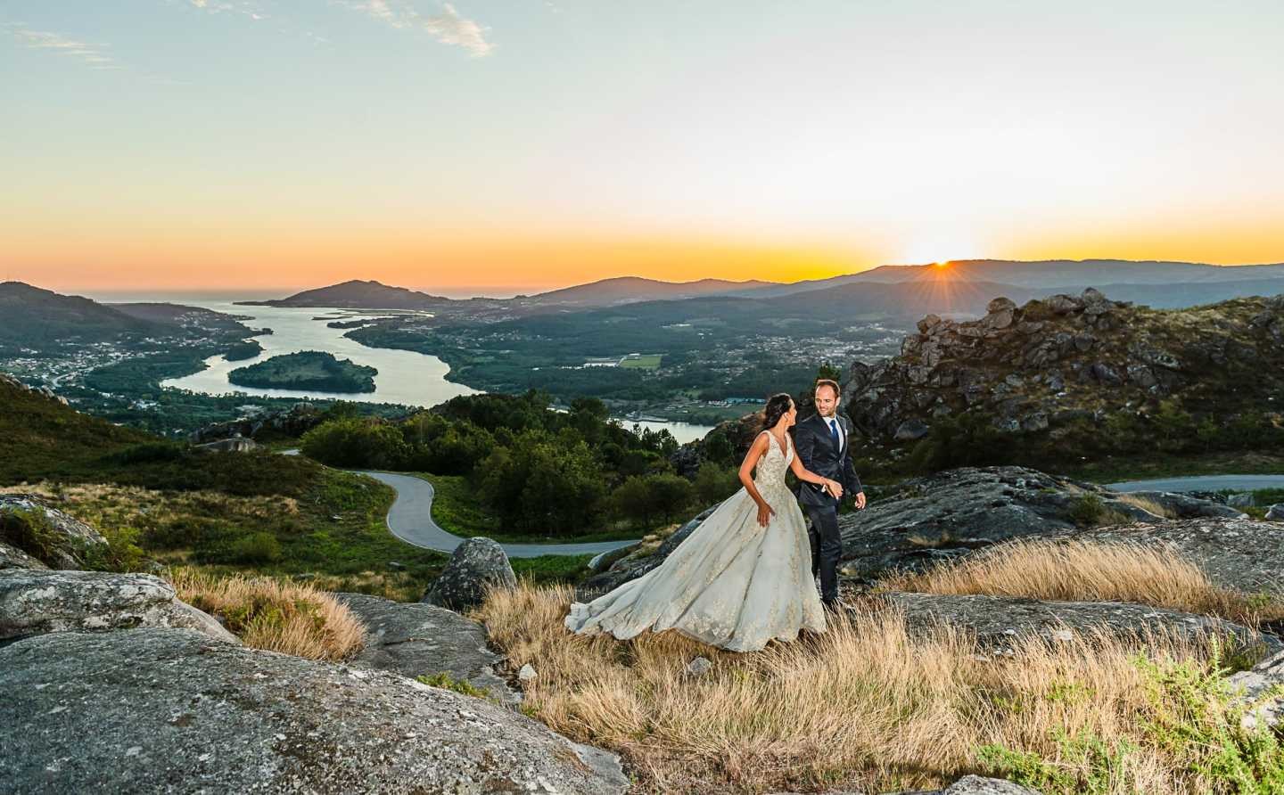 Noivos de mãos dadas a caminharem pelas as rochas