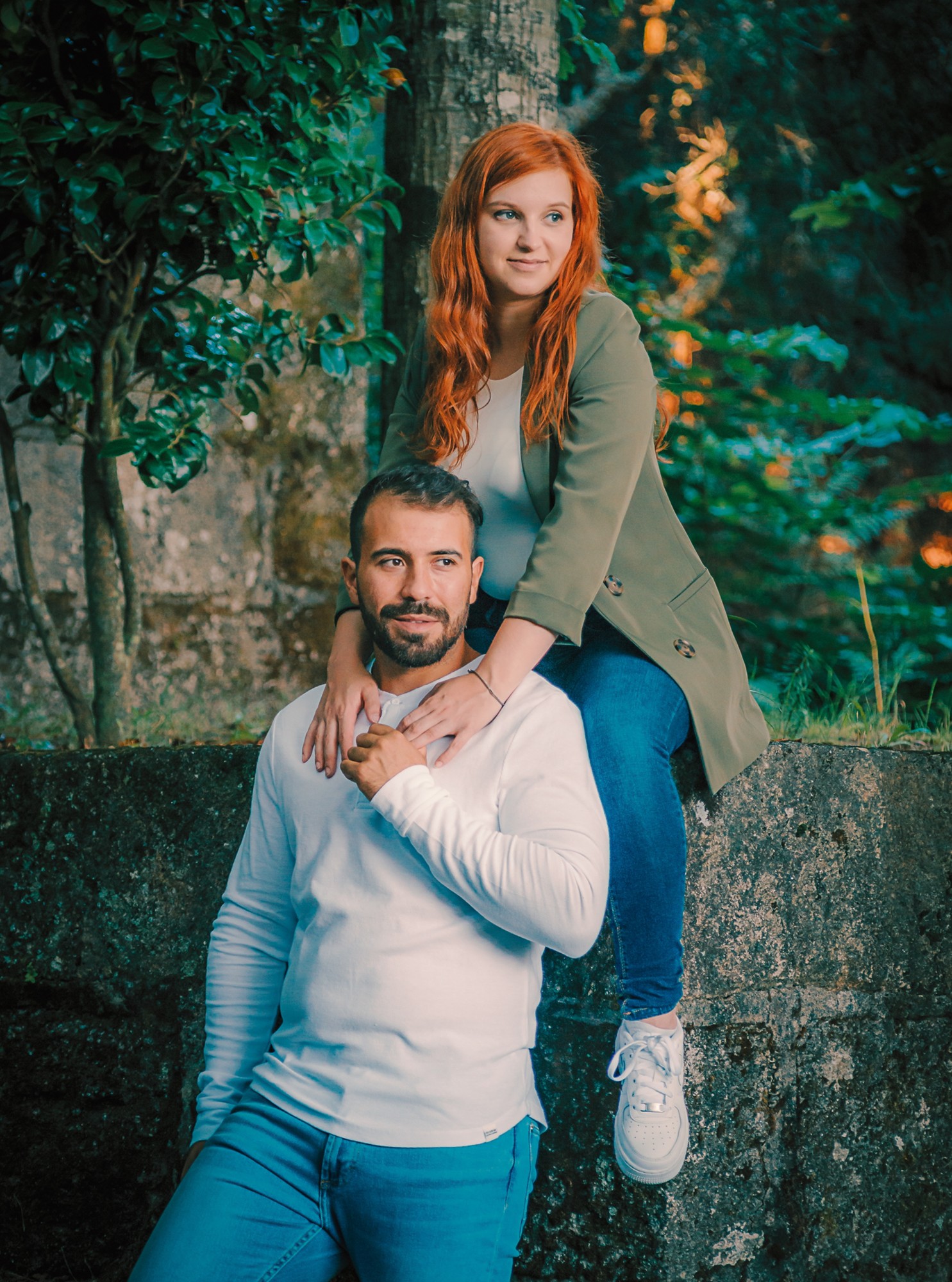 Marco em pé encostado na parede enquanto a Madga está sentada no muro