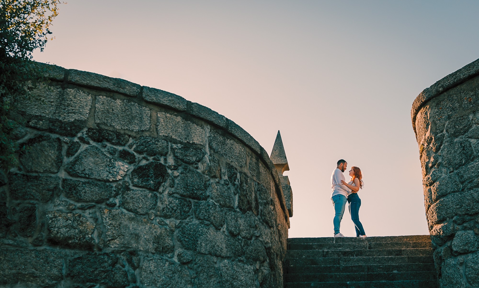 Casal em cima das escadas a darem um abraço enquanto olham um para o outro apaixonadamente