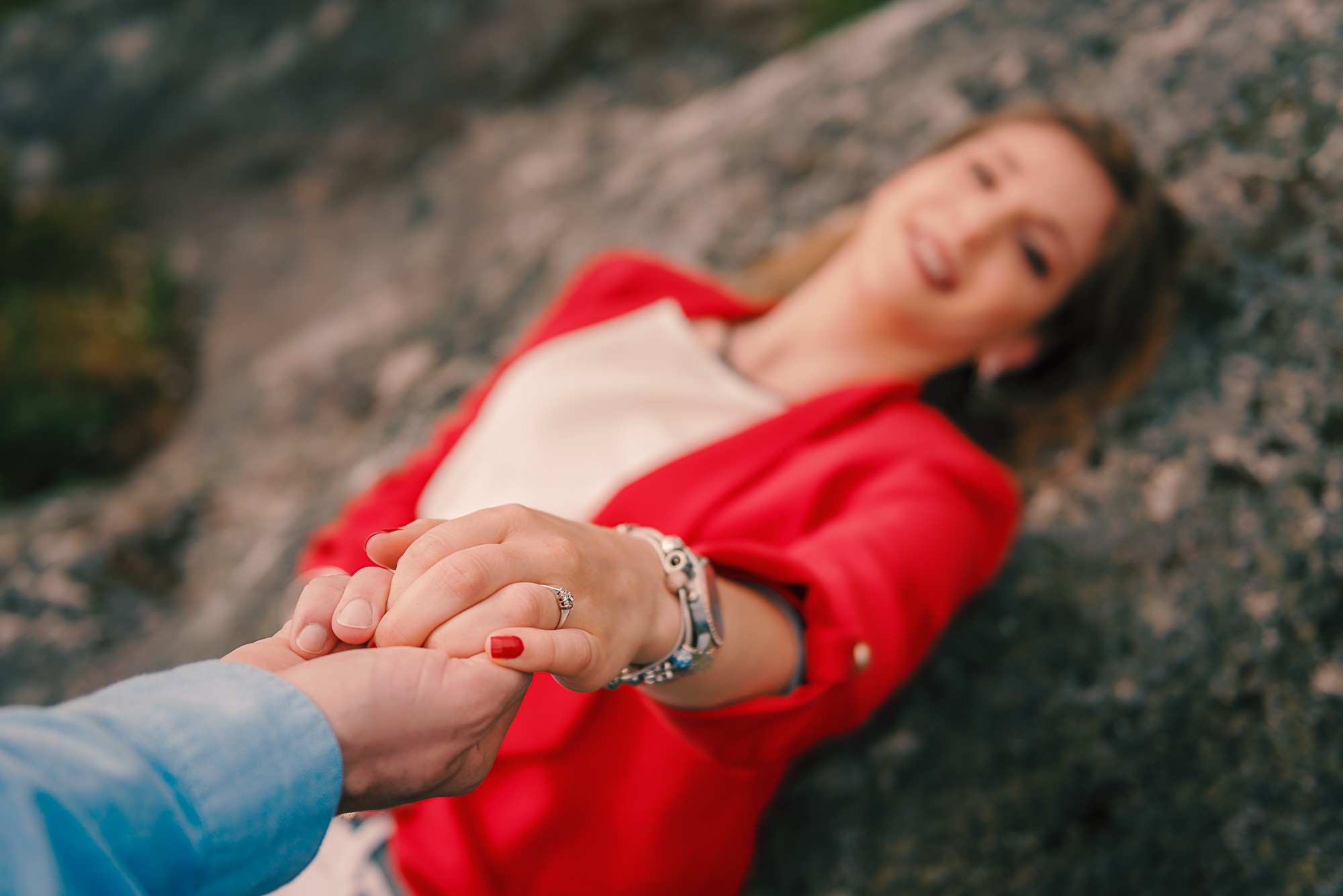 Nazaré deitada na rocha enquanto da a mão ao Artur