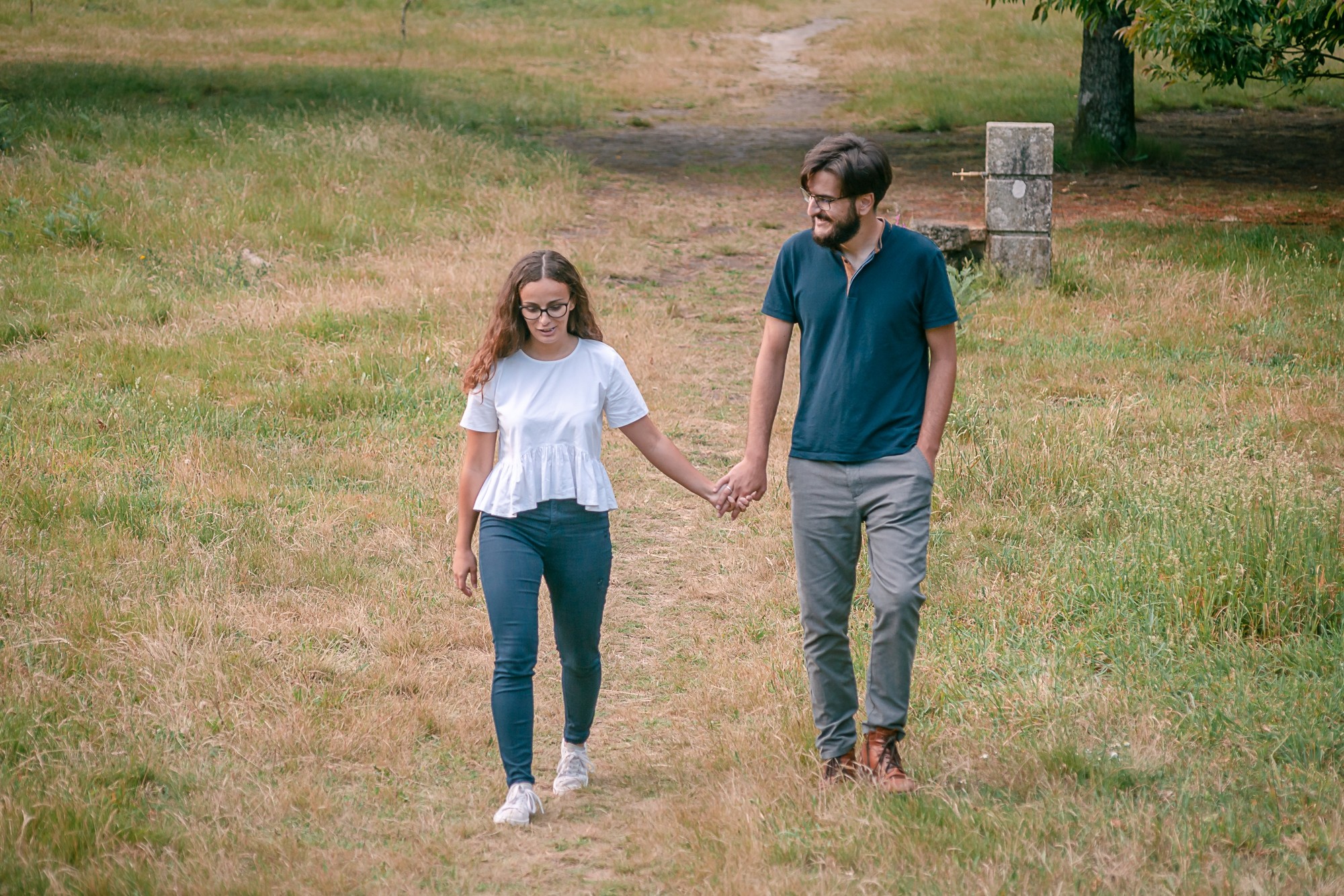 Casal a caminhar pela a relva de mãos dadas