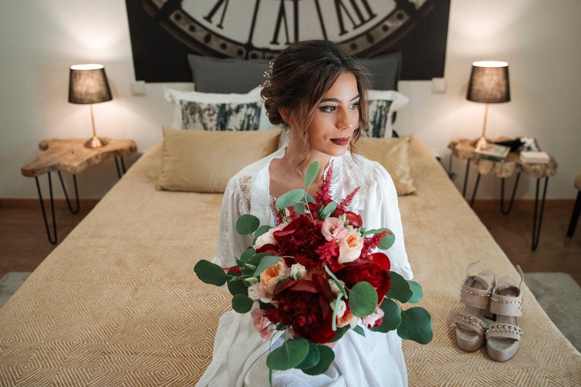 Noiva sentada na cama a segurar o buque