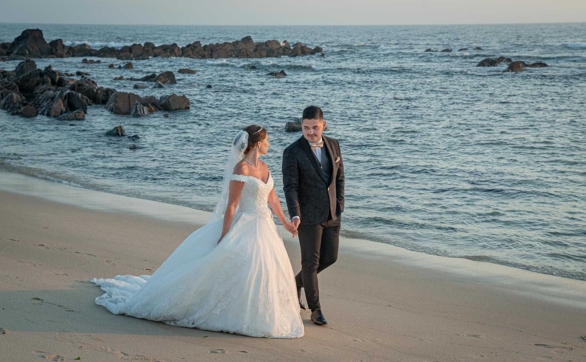 Casal a caminhar na praia de mãos dadas