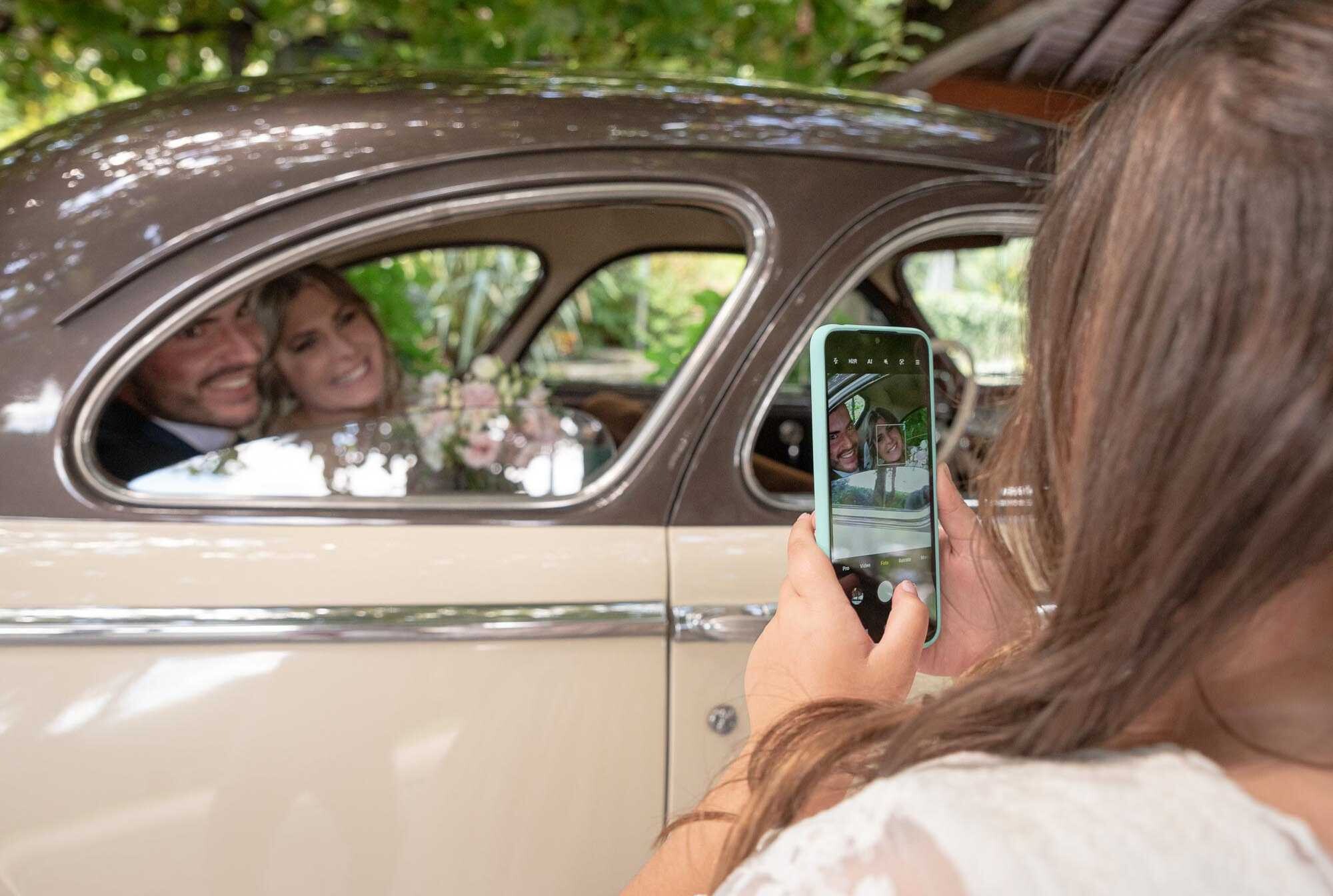 Madrinha a tirar foto dos noivos no carro