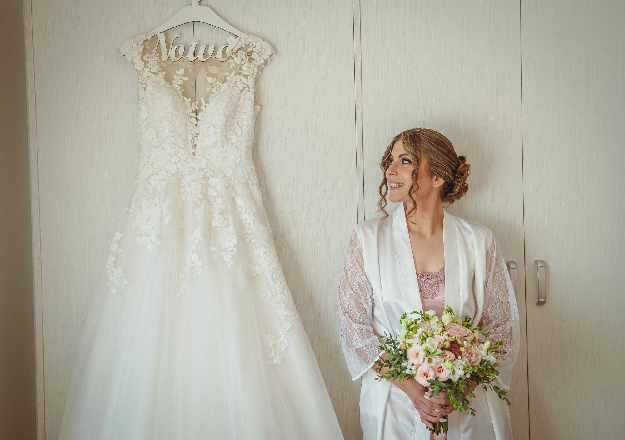 Noiva a olhar para o vestido enquanto segura o buque