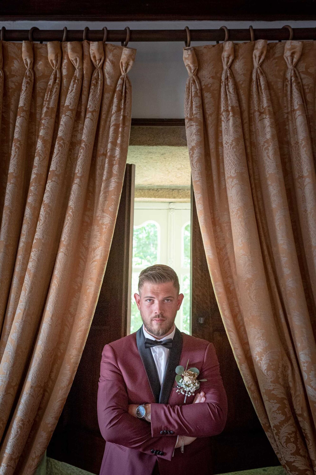 Noivo de braços cruzados no meio das cortinas