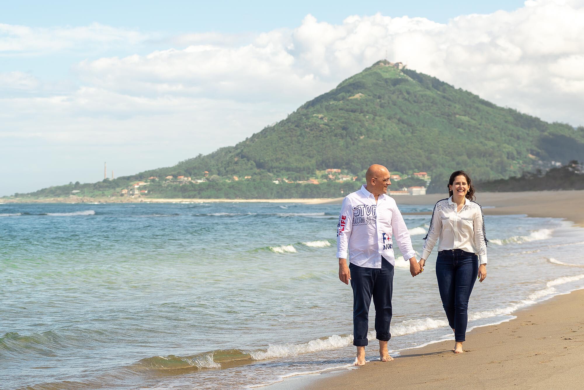 Noivos a caminharem na praia de mãos dadas