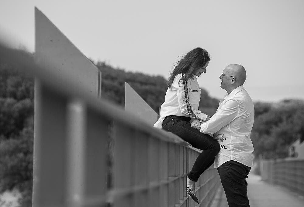 Mulher sentada na beira da ponte enquanto o homem fica a olhar para ela