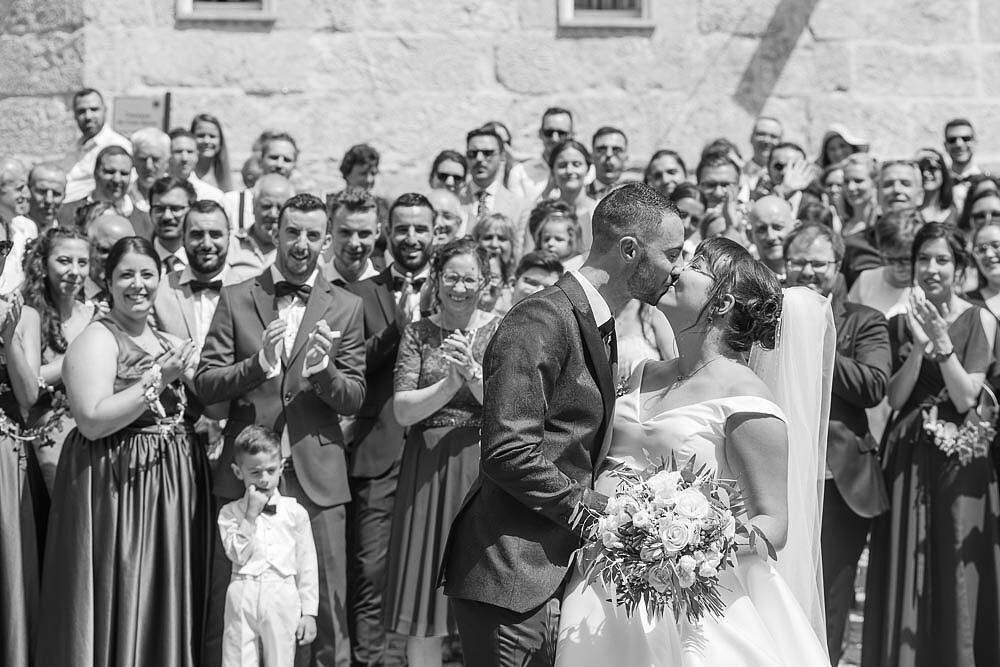 Casal a dar um beijo e com os convidados atrás