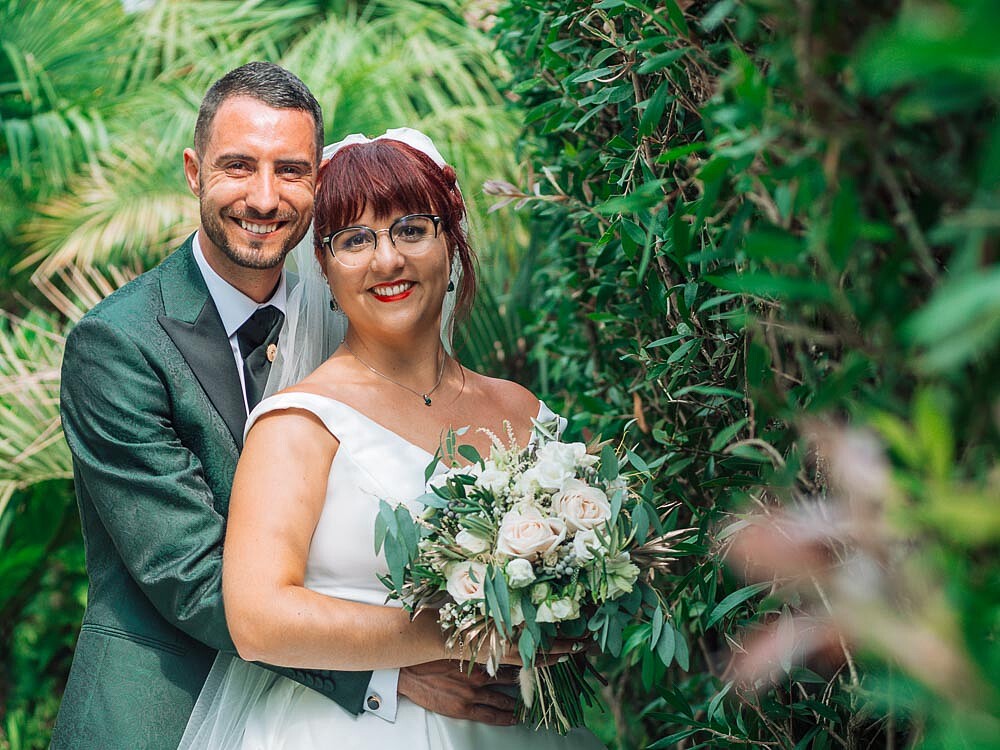 Homem a abraçar a Mulher por trás enquanto ela segura o buque