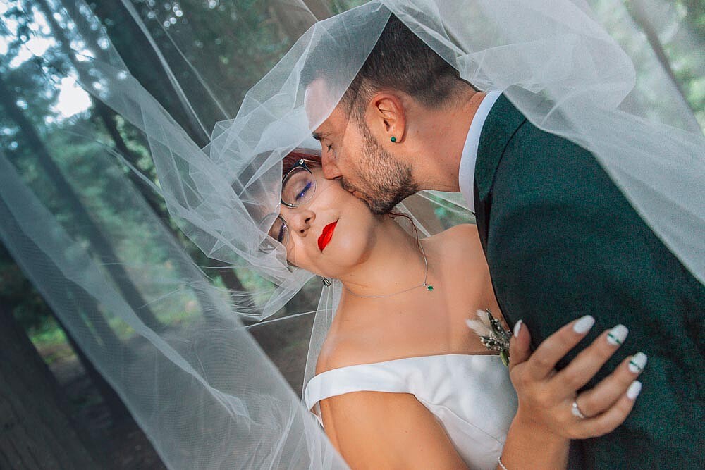 Pós Casamento :: Véu a voar enquanto o homem dá um beijo na bochecha da Esposa