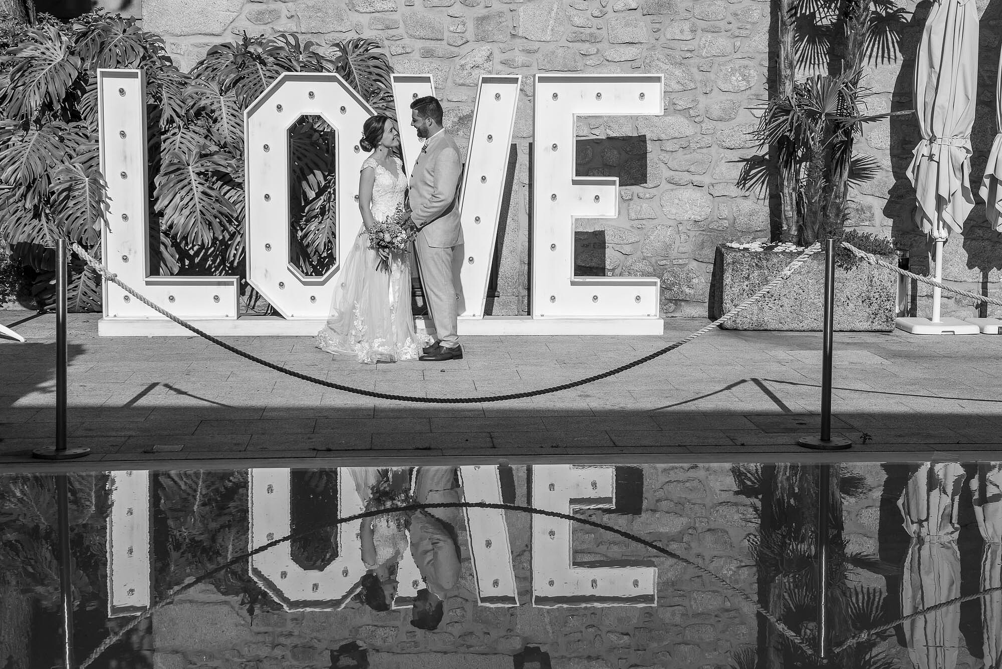 Casal a frente da placa onde diz "LOVE"