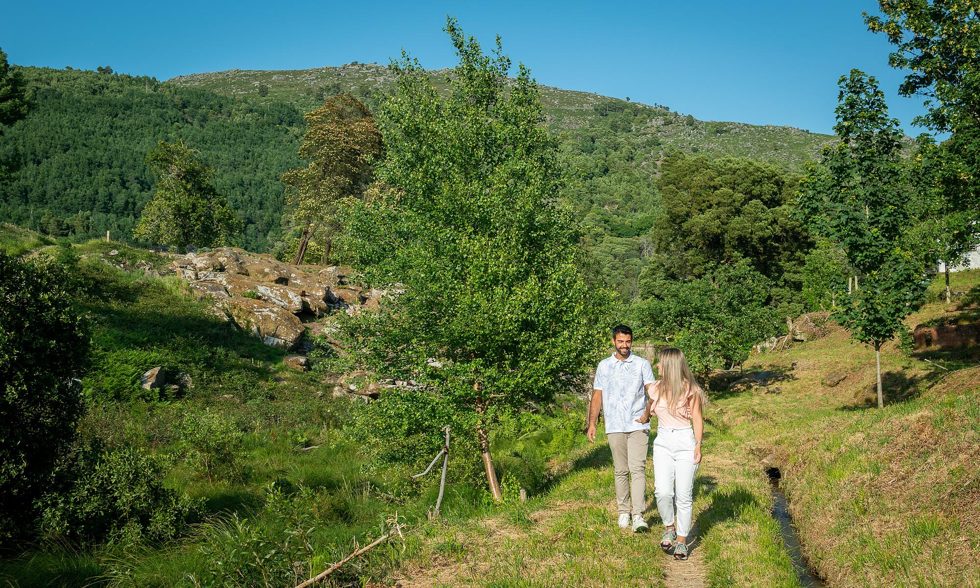 Casal a caminhar pela o relevo da montanha