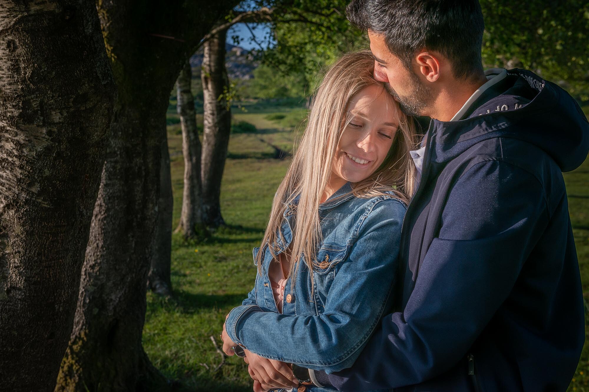 Homem a dar um beijo na testa a namorada enquanto a abraça por trás
