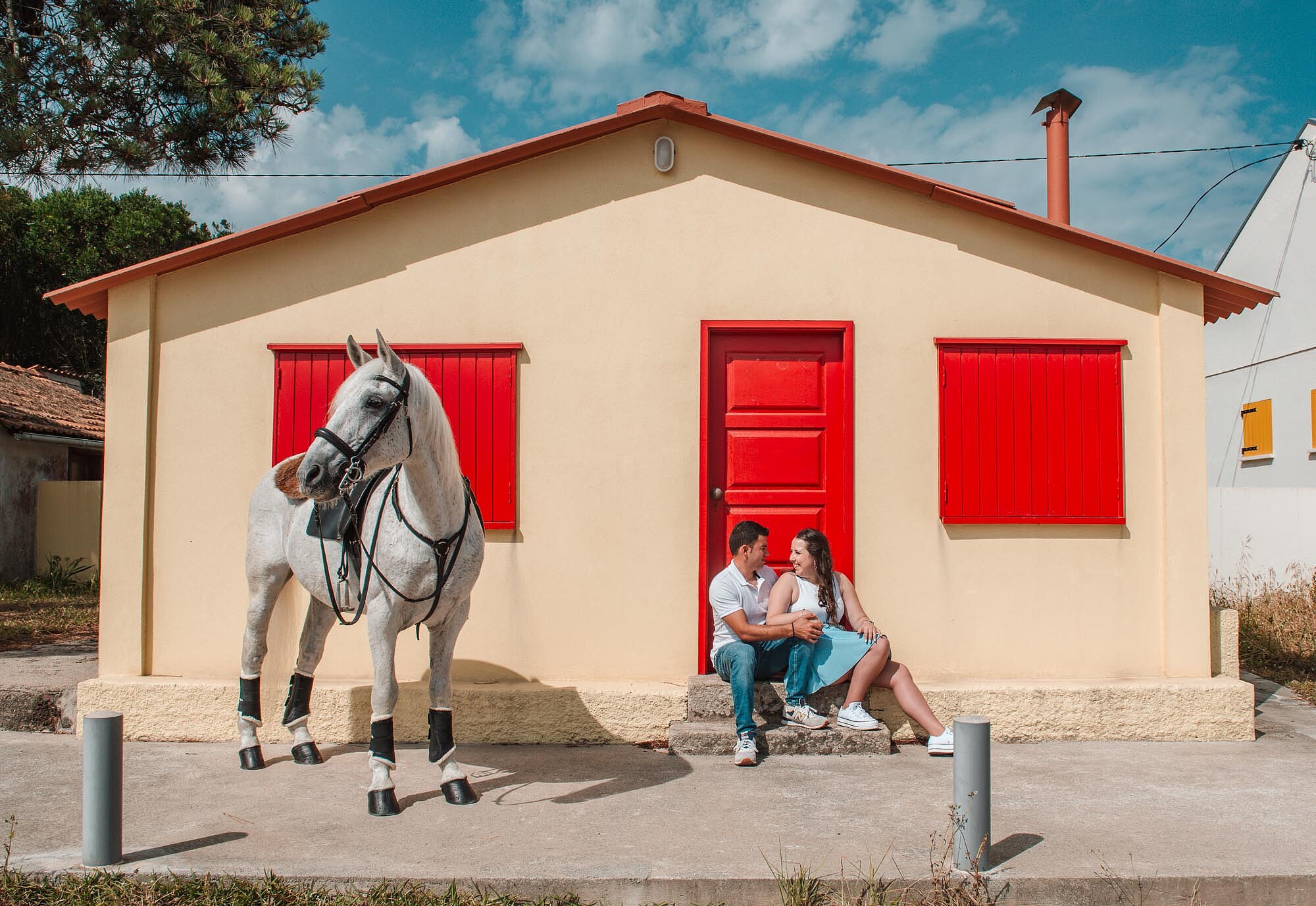 Casal a conversar nas escadas da casa enquanto o cavalo est&aacute; ao lado