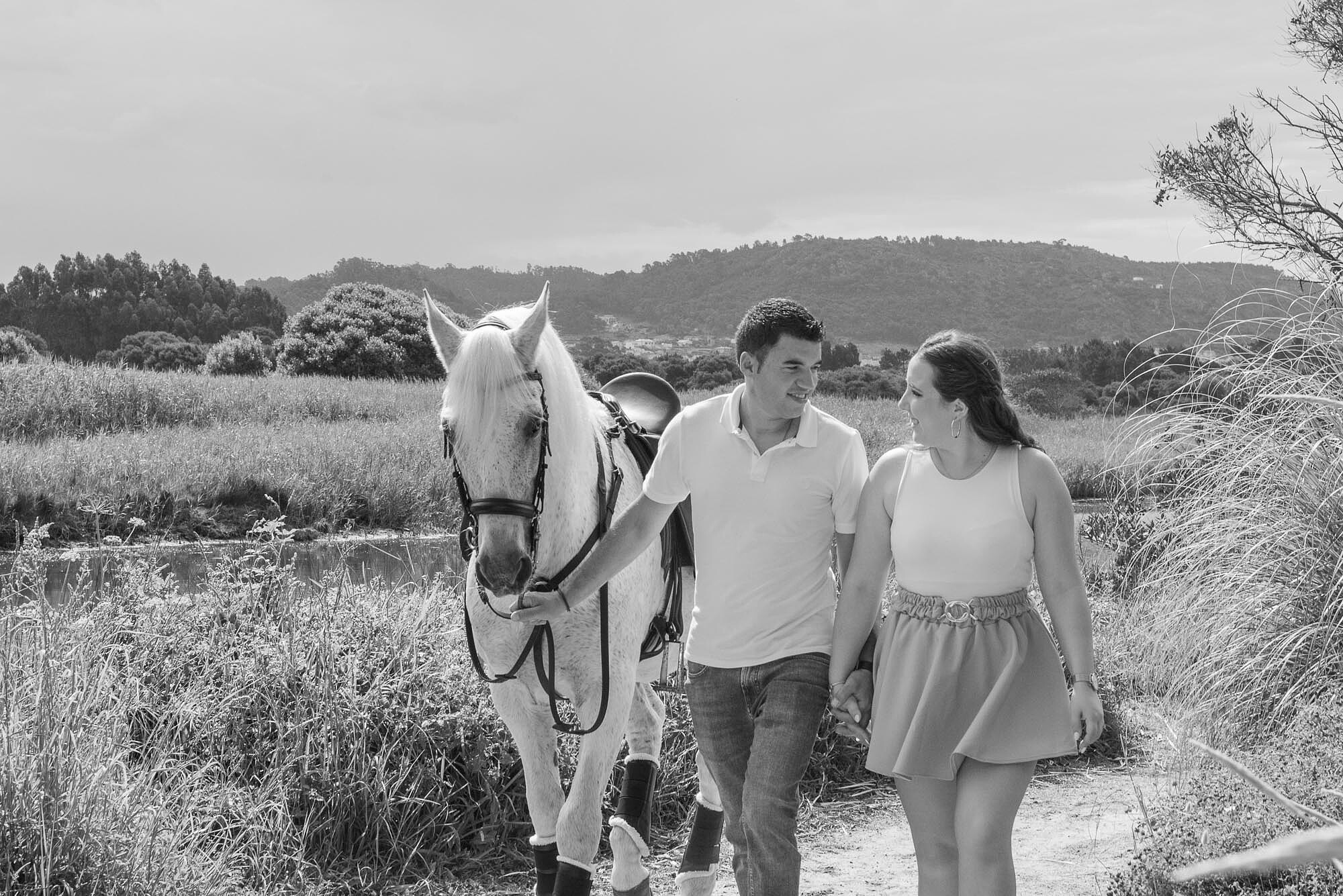 Casal a conversar enquanto caminham com o cavalo no bosque