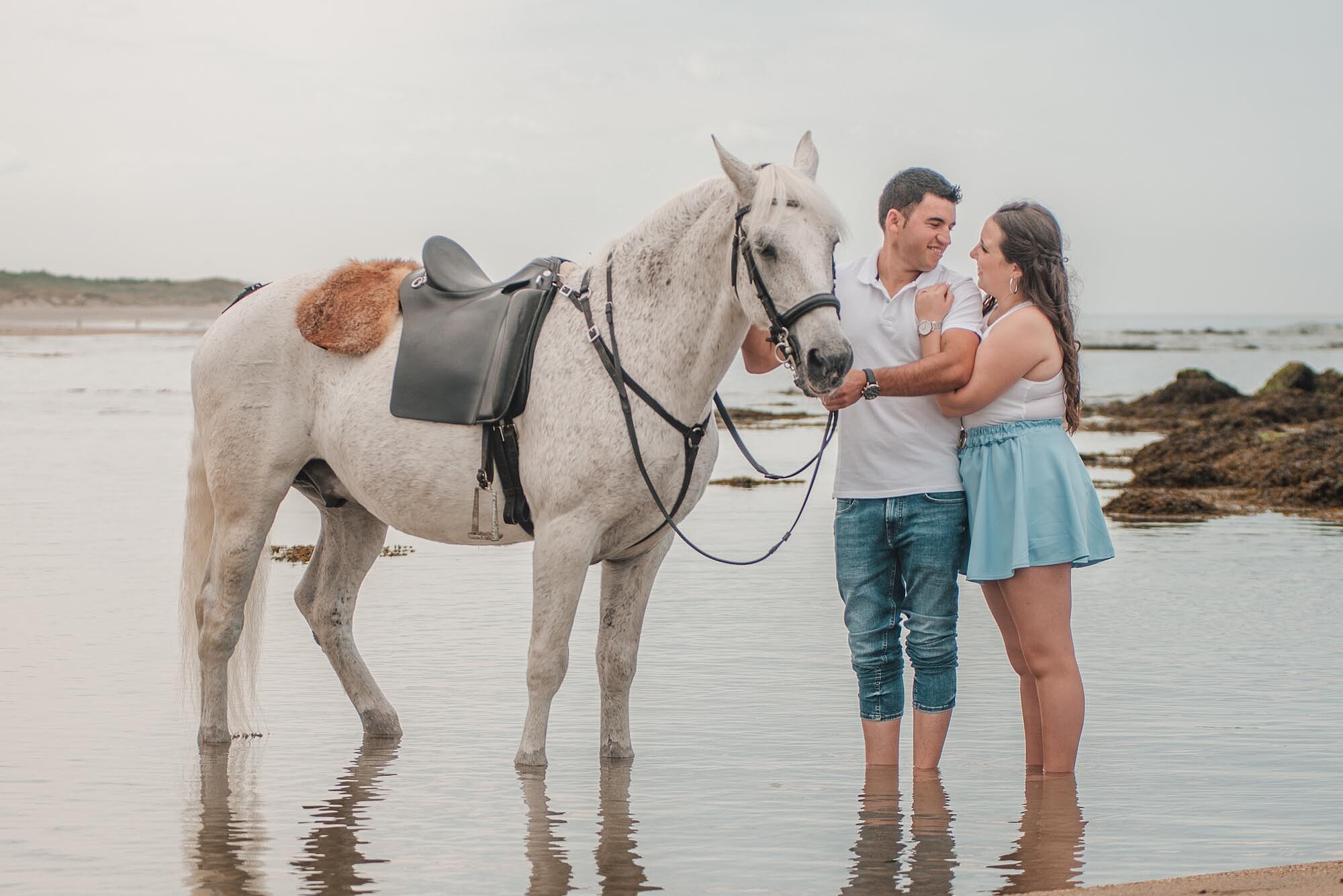 Mulher a abra&ccedil;ar por tr&aacute;s o namorado enquanto ele faz carinho no cavalo