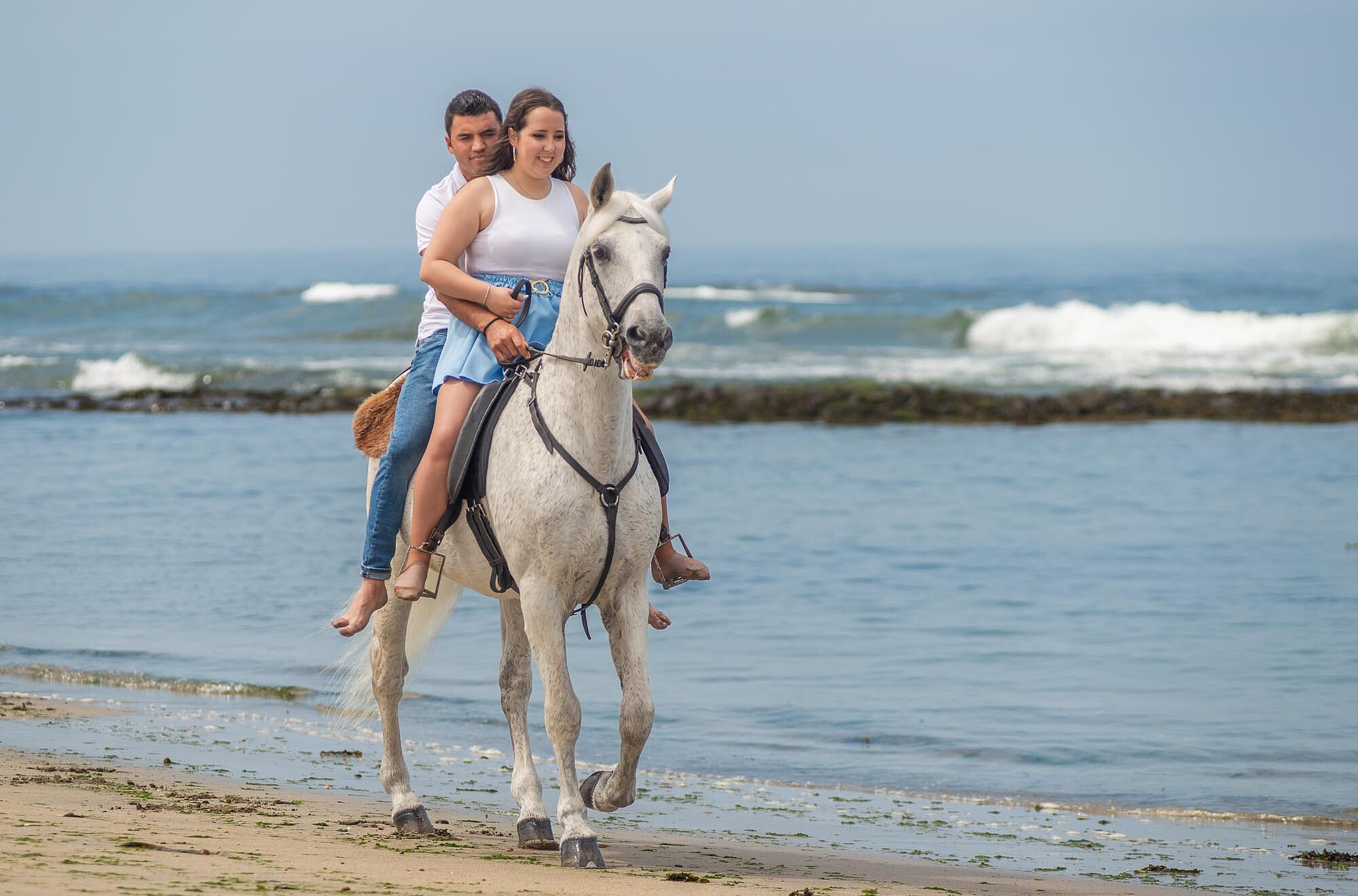 Casal a andar de cavalo a beira mar