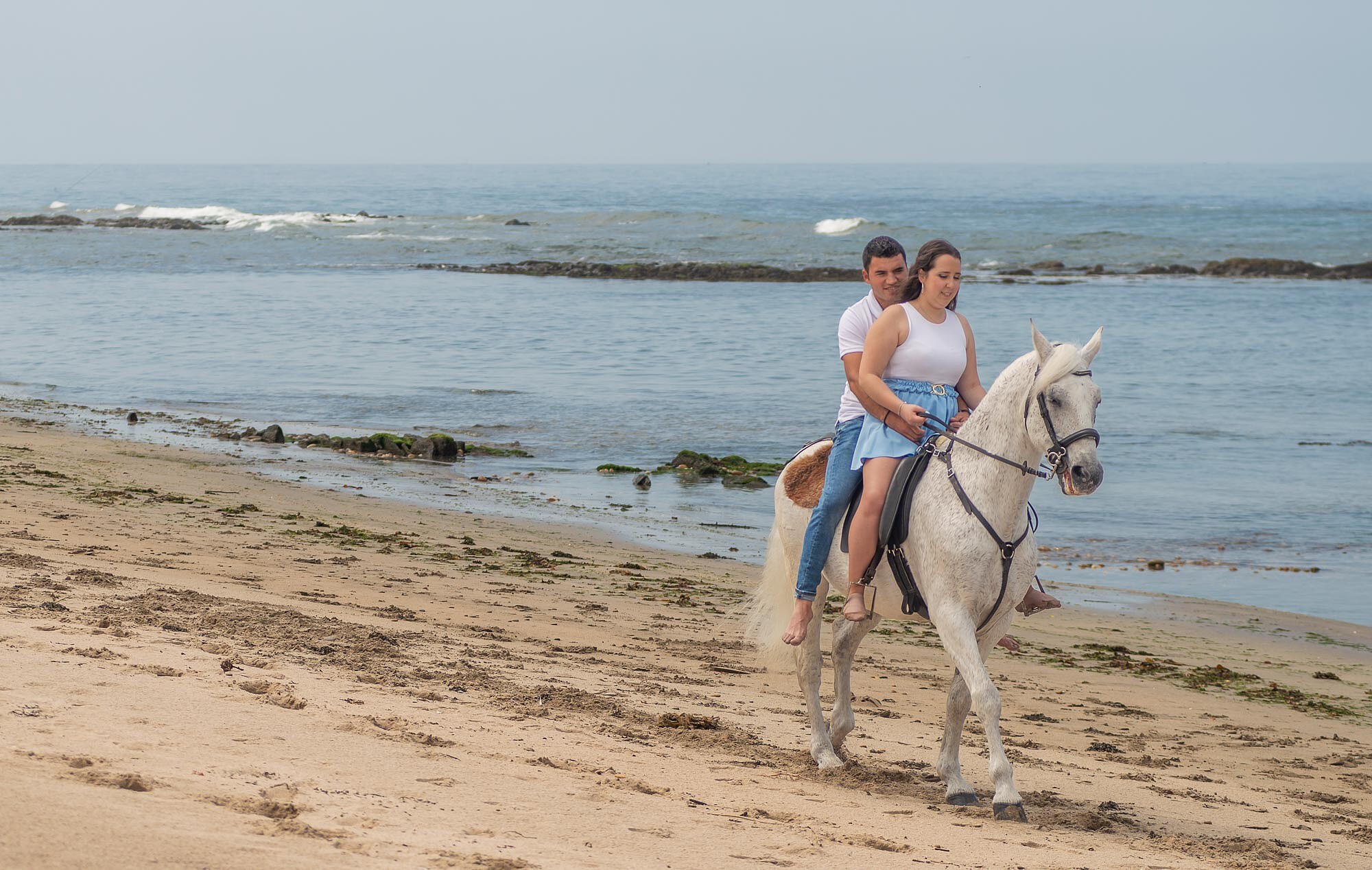 Casal a andar de cavalo na areia