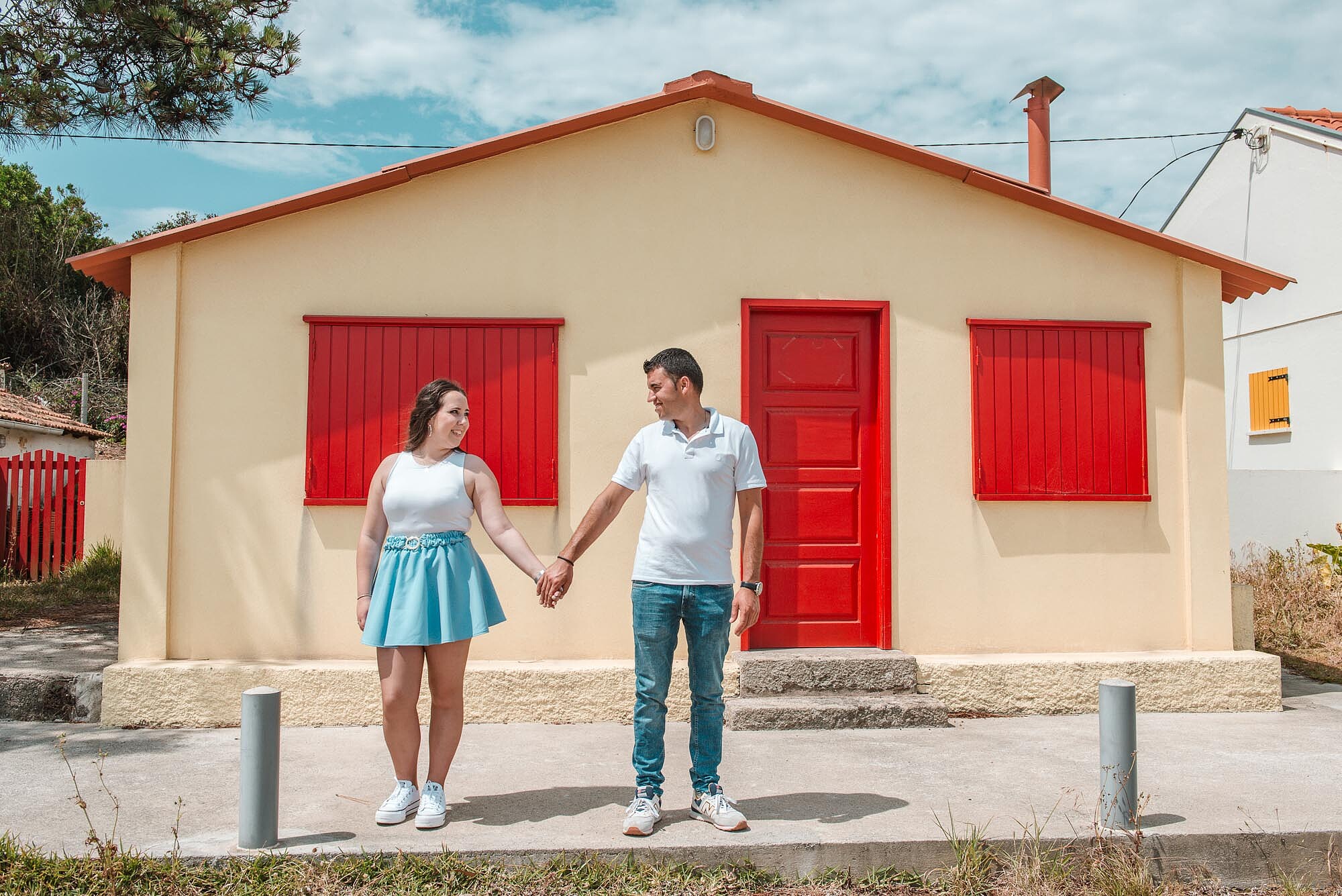 Casal de m&atilde;os dadas a frente de casa e a olharem um para o outro
