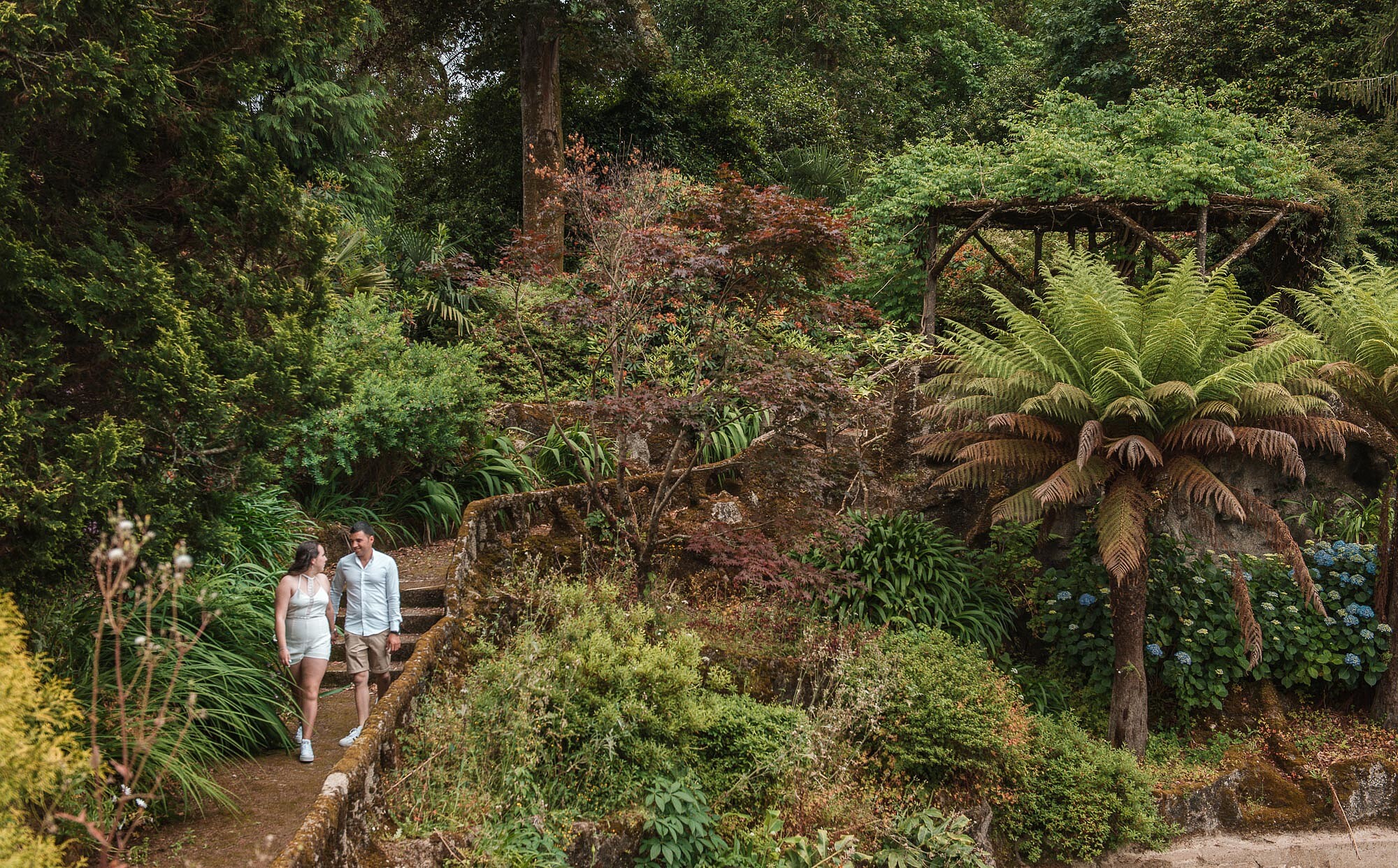 Casal a caminhar pelo um jardim e a conversar